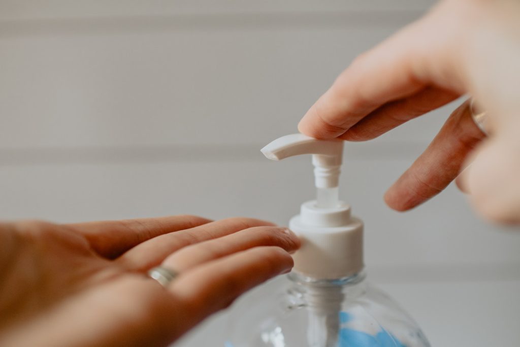 Woman applying hand sanitizer, demonstrating health and safety during the return to office